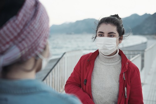 Women talking on the beach with face mask