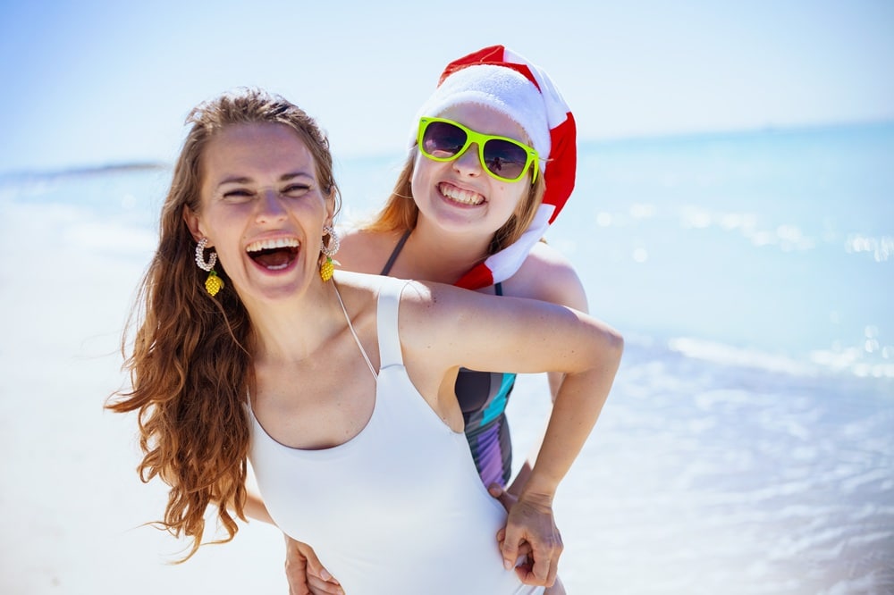 smiling mother and teenage daughter at beach having fun time